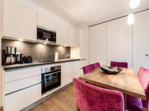 una cucina con tavolo in legno e sedie viola di Modern apartment in St Georgen near Salzburg a Fürstau