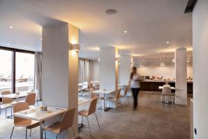 a woman walking through a restaurant with tables and chairs at Kriti Hotel in Chania Town