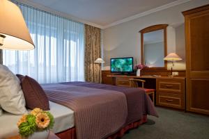 a hotel room with a bed and a desk and a mirror at Ensana Thermal Hévíz in Hévíz