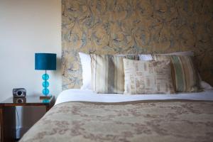 a bed with a headboard and pillows and a lamp at La Fosse at Cranborne in Cranborne