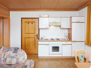 ミッタージルにあるSunny Hillside Apartment in Mittersill near Public Transportの白いキャビネットとソファ付きのキッチンが備わります。