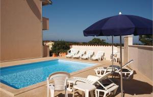 uma piscina com cadeiras brancas e um guarda-sol em 5 Bedroom Stunning Home In Liznjan em Ližnjan