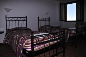 two twin beds in a room with a window at Agriturismo Rocca su Moru in Arbus