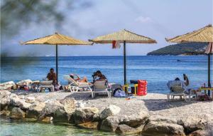 a group of people sitting on a beach with umbrellas at Beautiful Apartment In Slatine With 1 Bedrooms And Wifi in Slatine