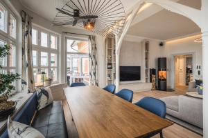 a living room with a wooden table and blue chairs at Goldmädchen 93 - Beletage in Timmendorfer Strand