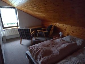 um quarto com uma cama, 2 cadeiras e uma janela em Apartmán u Kynských em Horní Lánov