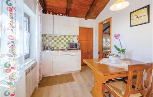 a kitchen with white cabinets and a wooden table at Amazing Home In Pobri With House Sea View in Volosko