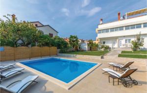 a swimming pool with chairs and a house at Beautiful Apartment In Novigrad in Novigrad Istria