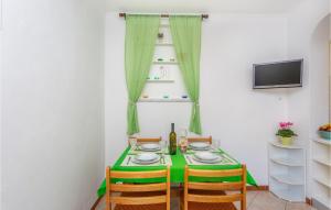 a green table with chairs and a bottle of wine at 2 Bedroom Cozy Apartment In Omisalj in Omišalj