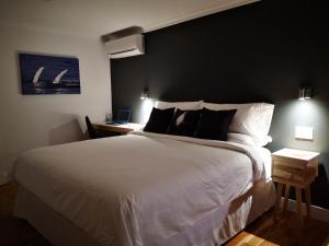 - une chambre avec un grand lit blanc et un mur noir dans l'établissement Au Cachalot Caché le gîte hôtel, à Tadoussac