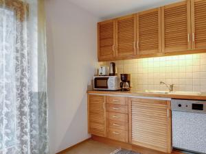 Apartment near the ski area in Matrei في ماتري إن أوستيرول: مطبخ بدولاب خشبي ومغسلة وميكروويف