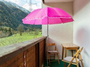 a pink umbrella on a balcony with a table and chair at Apartment near the ski area in Matrei in Matrei in Osttirol