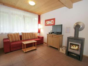 a living room with a red couch and a fireplace at Wood chalet in Styria with terrace in Eisenerz