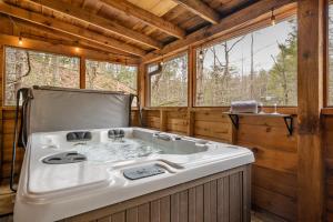 a bath tub in a wooden room with windows at The Robins Nest with hot tub in Pigeon Forge