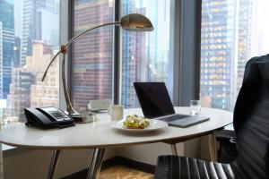 a desk with a laptop and a plate of food on it at InterContinental New York Times Square by IHG in New York