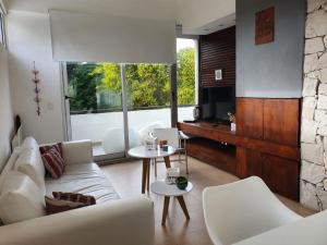 a living room with a white couch and a television at Punta vacaciones -piscina solo en vacaciones y fines de semana largos- in Las Gaviotas