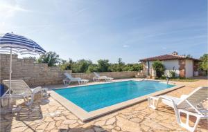 a swimming pool with two chairs and an umbrella at Nice Home In Baderna With House A Panoramic View in Baderna