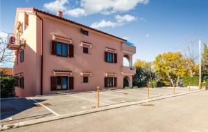 a pink building with a tennis court in front of it at Cozy Apartment In Njivice With Wifi in Njivice