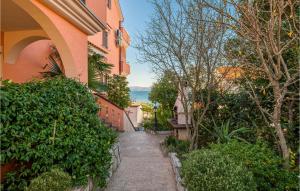 a walkway between two buildings with bushes and trees at Cozy Apartment In Njivice With Wifi in Njivice +10 photos