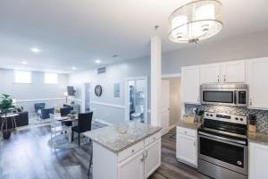 a kitchen with white cabinets and a living room with a table at Sanctuary Co 204 Loft Downtown Johnson City in Johnson City