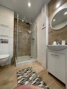 a bathroom with a shower and a sink and a mirror at Apartament PARYŻ in Białystok