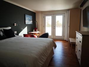 a hotel room with a bed and a sliding glass door at Au Cachalot Caché le gîte hôtel in Tadoussac