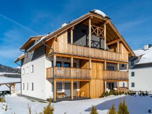 a house with a wrap around deck in the snow at Wooden chalet in Mauterndorf near Cross Country Meadows in Mauterndorf