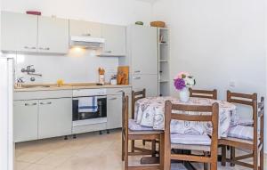 eine Küche mit einem Tisch und Stühlen sowie eine Küche mit weißen Schränken in der Unterkunft Awesome Home In Klenovica With 3 Bedrooms And Wifi in Klenovica