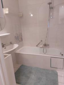 ein weißes Badezimmer mit einer Badewanne und einem Waschbecken in der Unterkunft Koksijde Gabbiano 104 en parking in Koksijde