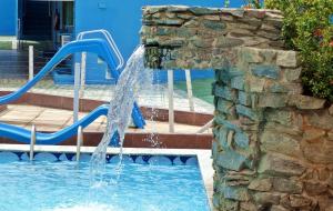 a water fountain in a pool with a slide at Hotel Oásis in Açu