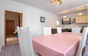 a dining room with a pink table and white chairs at Stunning Home In Dolac With 5 Bedrooms And Wifi in Primošten