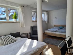 een slaapkamer met 2 bedden, een stoel en ramen bij Apartment Familie Grünauer in Sankt Johann im Pongau