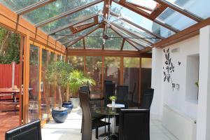 une véranda avec un toit en verre, une table et des chaises dans l'établissement Skylark Guest House, à Hounslow