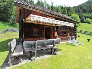 una cabaña de madera con dos bancos delante en Chalet in Obervellach in Carinthia, en Obervellach