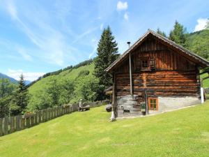 a log cabin in a field with a fence at Chalet in Obervellach Carinthia in Obervellach