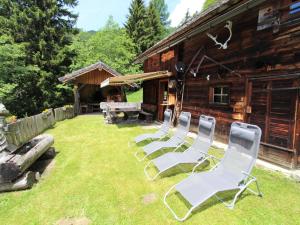 un groupe de chaises assises devant une cabine dans l'établissement Chalet in Obervellach in Carinthia, à Obervellach
