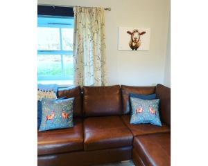 a brown leather couch in a room with a window at Swallow Cottage in Ripon