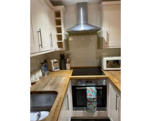 a kitchen with white cabinets and a stove top oven at Swallow Cottage in Ripon