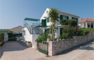 a white house with a stone wall and a palm tree at Holiday Home Segvica V in Rogač