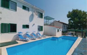 a swimming pool in front of a building with blue chairs at Beautiful Home In Rogac With House Sea View in Rogač