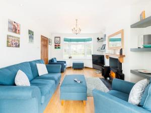 uma sala de estar com sofás azuis e uma televisão em Pass the Keys SPACIOUS Modern 5 Bed, Sleeps up to 12 & Parking em Warwick