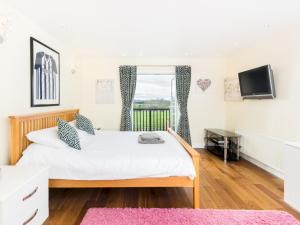 um quarto com uma cama grande e uma televisão em Pass the Keys SPACIOUS Modern 5 Bed, Sleeps up to 12 & Parking em Warwick