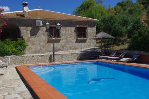 una piscina con 2 sillas y una casa en Finca Barreras, en El Gastor
