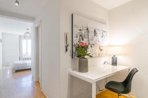 Dieses weiße Zimmer verfügt über einen Schreibtisch und eine Vase aus Blumen. in der Unterkunft Simplon 10 - Lausanne Gare in Lausanne