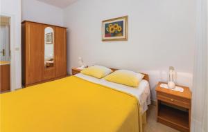 een slaapkamer met een geel bed en een houten kast bij Gorgeous Apartment In Rabac With Kitchen in Rabac