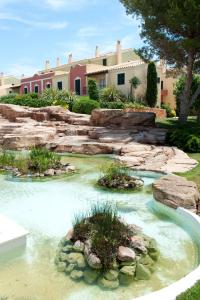 a garden with a pond in front of a house at Grupotel Playa Club in Son Xoriguer