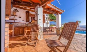 eine Terrasse mit 2 Stühlen, einem Tisch und einer Küche in der Unterkunft Casa la serena in Iznájar