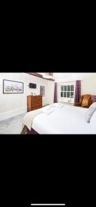 a bedroom with a large white bed and purple curtains at The Red Lion in Sedbergh