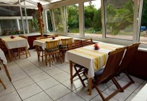 a restaurant with tables and chairs in a room with windows at Pension Zum Froschkönig in Lübbenau