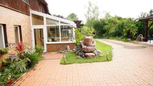 ein großer Teddybär sitzt auf dem Gras vor einem Haus in der Unterkunft Pension Zum Froschkönig in Lübbenau